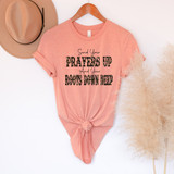 Send Your Prayers Up And Your Roots Down Deep DTF Heat Transfer T-shirt, pink casual t-shirt with motivational quote, displayed with a beige hat and decorative pampas grass.
