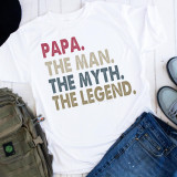 Papa The Man The Myth The Legend Sublimation Transfer - A white T-shirt with colorful text and arranged around casual items and shoes.