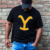 Yellow Y DTF Heat Transfer, person wearing black T-shirt with yellow logo on front and denim jeans, standing against a brick wall.
