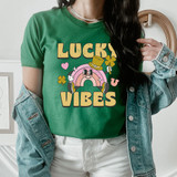Lucky Vibes DTF Heat Transfer, image of a woman wearing a green T-shirt with a colorful St. Patrick's Day themed design of a rainbow, leprechaun hat, clovers, and the words 'Lucky Vibes'.