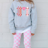 Love More Skateboard DTF Heat Transfer, colorful skateboard and heart-shaped lollipop design on a gray sweatshirt worn by a person with pink-checkered pants.