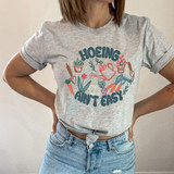 Hoeing Ain't Easy DTF Heat Transfer T-shirt, graphic tee with gardening tools and plants design.