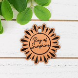 Ray of Sunshine Tan Leather Keychain, decorative sunburst-shaped keychain with black accents and the phrase 'Ray of Sunshine' engraved in the center.