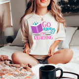 Go Away, I'm Reading DTF Heat Transfer, a colorful heat transfer design with an open book and stars, on a woman's T-shirt.