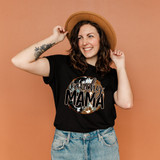 Ranchy Mama DTF Heat Transfer, woman wearing black t-shirt with ranchy mama graphic design, smiling and holding a tan hat, on orange background.