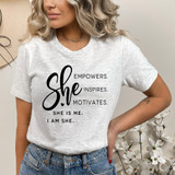 She Is Me I Am Her DTF Heat Transfer, a woman wearing a light grey T-shirt with empowering black text design.