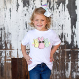 Retro Bunnies DTF Heat Transfer, a vibrant design featuring three pastel-colored bunnies with one in the middle wearing sunglasses, applied on a white T-shirt worn by a smiling young girl.