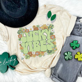 Lucky Vibes Floral DTF Heat Transfer, colorful floral design with bold text on a beige T-shirt surrounded by St. Patrick's Day decorations.