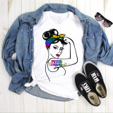 Proud Mama Pride Rosie The Riveter Pin Up Girl Sublimation Transfer, graphic design of a woman with a rainbow-colored bandana, black hair, green eyes, and red lipstick, with patriotic 'Proud Mama' text, on a white t-shirt laid on a flat surface with denim jacket, black sneakers, and sunglasses.