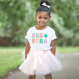 Eggstra Chenille 'look' DTF Heat Transfer, girl wearing a white T-shirt with colorful 'EGG' and 'STRA' lettering and a pink tutu skirt outdoors.