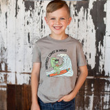 Happiness Comes In Waves DTF Heat Transfer, a boy wearing a grey T-shirt with a fun surfing dinosaur graphic and the phrase 'Happiness Comes In Waves'.