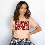 She Cooks to 90s Country And Does Her Makeup To Trap Music DTF Heat Transfer, a woman wearing a beige t-shirt with text and plaid shirt tied around her waist.