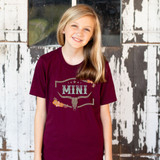 Mini Bullhead DTF Heat Transfer, decorative design with a bull skull and floral accents on a maroon T-shirt worn by a smiling girl.