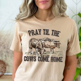 Pray Till The Cows Come Home Screen Print Heat Transfer, a beige t-shirt with a farm-themed illustration of cows and a barn, and the humorous phrase 'Pray Till The Cows Come Home' printed across the front.