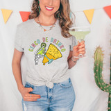 Cinco De Drinko DTF Heat Transfer, colorful graphic of a skeleton holding a margarita and a taco on a woman's t-shirt, celebrating Cinco de Mayo with festive party decorations and a cactus in the background.