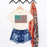 Stone USA Flag Screen Print Heat Transfer, fabric heat transfer design of the United States flag with animal print patterns and red, white, and blue colors displayed on a cream t-shirt, with denim shorts and a red and blue patterned scarf in the background.