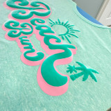 Beach Bum PUFF Screen Print Heat Transfer, vibrant turquoise and pink design with a sun, palm trees, and text on a light green fabric shirt.