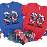 SD Stars & Stripes DTF Heat Transfer, patriotic American flag design on blue and red T-shirts with South Dakota text, along with American flag accessories.