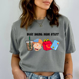 Busy Doing Mom Stuff Blue/Orange DTF Heat Transfer, humorous graphic of a drink, a woman, a shopping bag, and a credit card on a gray t-shirt.