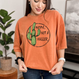Not A Hugger DTF Heat Transfer, graphic of a cactus and the text 'Nope, Not A Hugger' on an orange T-shirt worn by a woman.