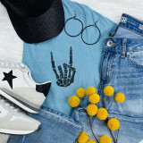 Rock On Black Skeleton Hand POCKET Screen Print Heat Transfer, flat lay of fashion apparel and accessories including a blue t-shirt with skeleton hand print, denim jeans, white sneakers with star design, black glittery cap, hoop earrings, and yellow pom-pom flowers.