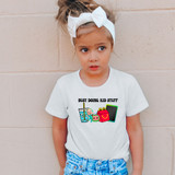 Busy Doing Kid Stuff Melon DTF Heat Transfer, a colorful cartoon design on a white children's t-shirt showing a drink, a character, a shopping bag, and a mobile phone.