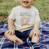 Shell Yeah DTF Heat Transfer, product on a child's white t-shirt with shell and starfish illustrations in orange color.