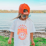 Summer Happy Face DTF Heat Transfer, a colorful and vibrant smiley face design with the word 'Summer' and sun rays, applied on a white T-shirt worn by a girl outdoors near a lake.