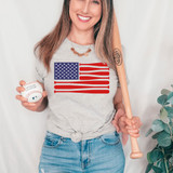 Baseball Flag DTF Heat Transfer, image of a woman holding a baseball and batting helmet, wearing a t-shirt with a flag design, and holding a baseball bat.