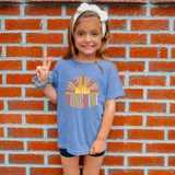 Be The Sunshine DTF Heat Transfer, colorful graphic design on a blue t-shirt worn by a smiling girl showing peace sign.