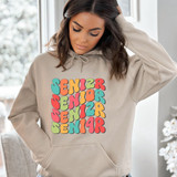 Senior 2024 Stacked DTF Heat Transfer, colorful stacked text on a beige hoodie worn by a woman.