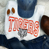 Tigers Orange PUFF Screen Print Heat Transfer, vibrant orange and black tiger logo on white fabric with 'TIGERS' text, displayed with jeans, denim cap, brown shoes, and earrings.
