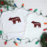 Sister Bear Sublimation, white T-shirts with red and black checkered bear designs with 'brother' and 'sister' text, surrounded by colorful Christmas string lights and pine branches.