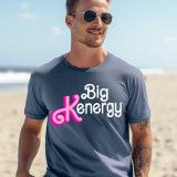 Big Kenergy DTF Heat Transfer, a vibrant, colorful design on a casual t-shirt worn by a smiling man at the beach.