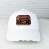 Soccer Mom Leather Hat Patch, white baseball cap with a brown leather patch featuring the words "Soccer Mom" along with a soccer ball and heart design
