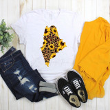 Maine Leopard Sunflower Sublimation Transfer, white T-shirt with a sunflower and leopard print map of Maine design, paired with ripped jeans, yellow jacket, and black sneakers.