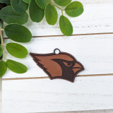 Cardinal Mascot Leather Keychain, brown and black leather keychain with cardinal bird design on a white wooden surface with green leaves.
