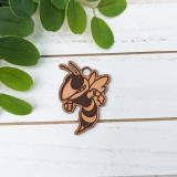 Yellowjacket Mascot Leather Keychain, a detailed cartoon-style yellowjacket insect keychain on a white wooden surface with green leaves.