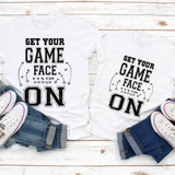 Get Your Game Face On Football Sublimation Transfer, two white T-shirts with football-themed text and design laid out on a white wooden surface, paired with denim jeans and white sneakers.