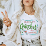 Drink Up It's Christmas DTF Heat Transfer, a woman wearing a white Christmas-themed t-shirt with a drink illustration and festive text.