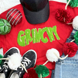 Grinchy Chenille Patch, green fluffy chenille patch spelling out 'GRINCHY' on a red T-shirt among Christmas decorations.