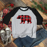 Mama Bear Screen Print Transfer, black and red buffalo plaid bear silhouette with the word Mama written in script across it, on a gray and black raglan shirt, surrounded by casual clothing and holiday decorations.