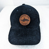 Respect The Locals Leather Hat Patch, round brown leather patch with shark design and 'Respect The Locals' text embroidered on a black corduroy cap.