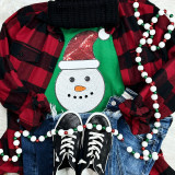 Sequin Snowman Patch, holiday winter clothing decoration with snowman face featuring a red sequined hat and orange carrot nose on a green shirt surrounded by a red plaid shirt, blue jeans, black sneakers, and Christmas bead garland.