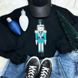 BLUE Nutcracker Sequins Embroidered Patch, a colorful sequin embroidered patch of a nutcracker soldier on black clothing surrounded by Christmas decorations and accessories.