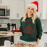 You Serious Clark? DTF Heat Transfer, Christmas themed image of a woman wearing a Santa hat and Christmas sweater with the text "You Serious Clark?," applying the heat transfer on a holiday sweater.