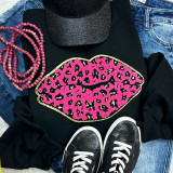 Pink Leopard Lips Chenille Patch, close-up of a pink leopard print lips patch on a black sweatshirt, with pink beaded necklace, black glitter cap, blue jeans, and black sneakers with white laces.