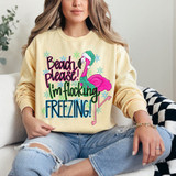 Beach Please! I'm Flocking Freezing! DTF Heat Transfer, humorous colorful sweatshirt with a pink flamingo wearing a Christmas hat, surrounded by snowflakes.