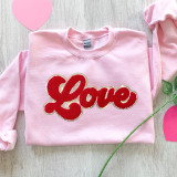RED LOVE Chenille Patch, pink sweatshirt with red embroidered 'Love' patch.