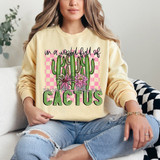 Be A Cactus DTF Heat Transfer, illustrated cactus and flower design on a light yellow sweatshirt worn by a woman.